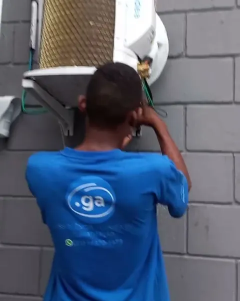 Técnico com a camiseta da GA mexendo numa condensadora
